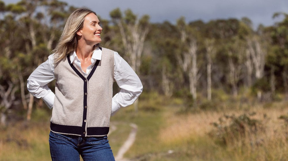 Woman wearing a Merino Wool See Saw beige vest with navy trim and white shirt outdoors