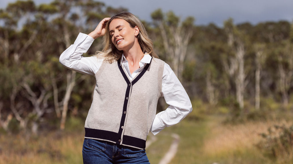 Woman wearing a Merino Wool See Saw beige vest with navy trim and white shirt outdoors