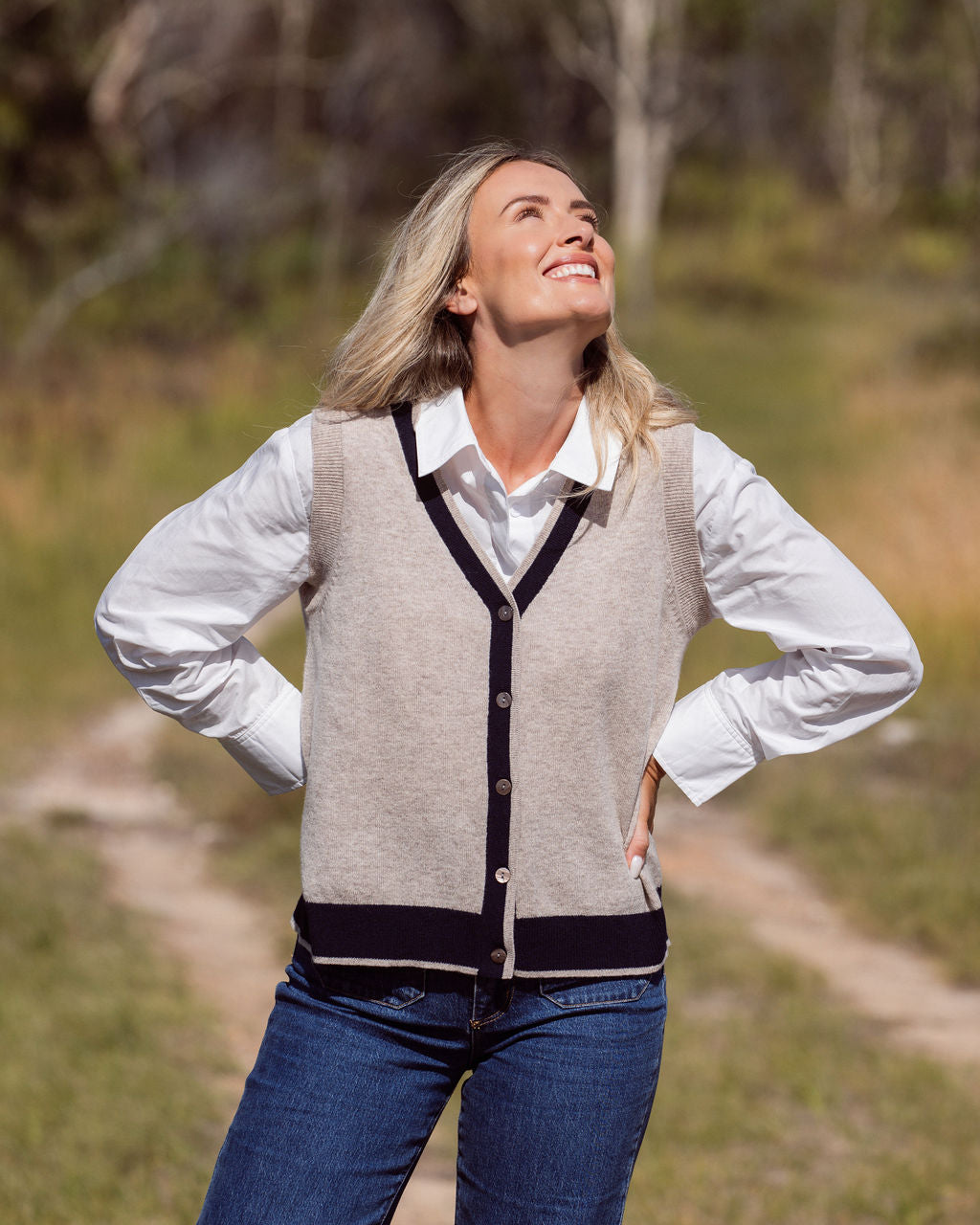 Woman wearing a Merino Wool See Saw beige vest with navy trim and white shirt outdoors