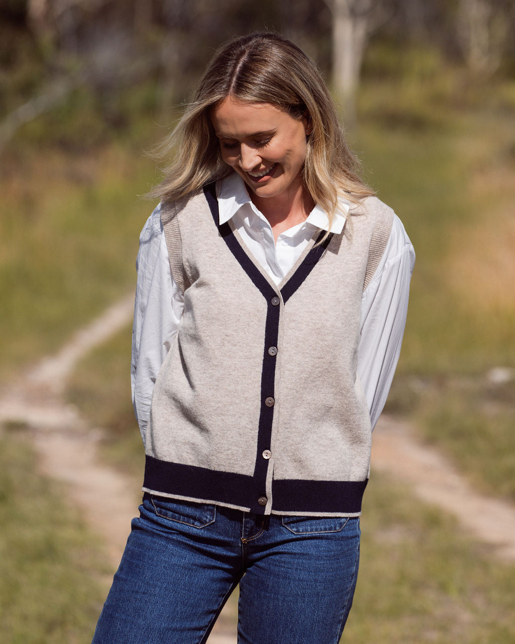 Woman wearing a Merino Wool See Saw beige vest with navy trim and white shirt outdoors