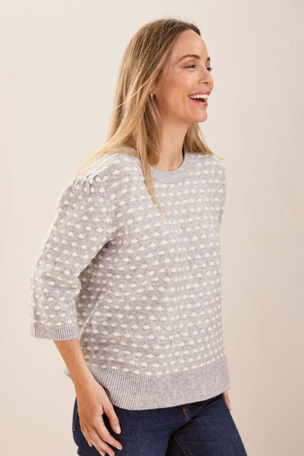 Woman wearing a patterned silver and white See Saw sweater against a plain background
