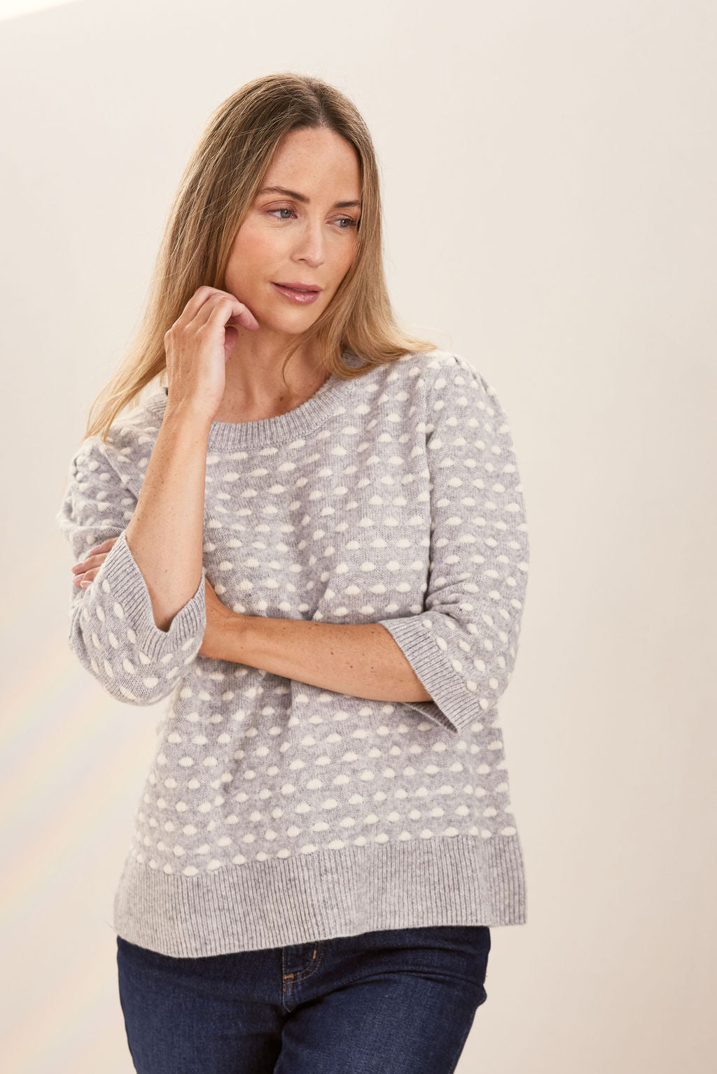 Woman wearing a patterned silver and white See Saw sweater against a plain background