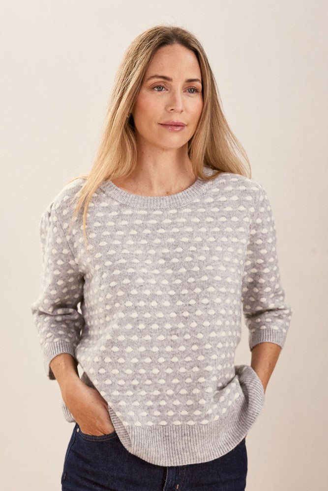 Woman wearing a patterned silver and white See Saw sweater against a plain background