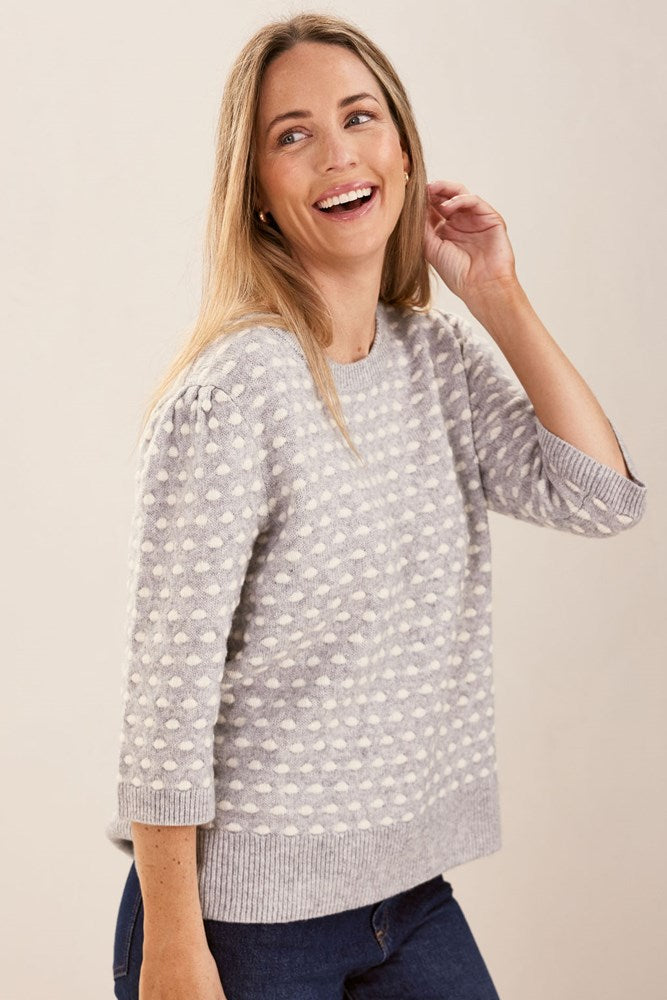 Woman wearing a patterned silver and white See Saw sweater against a plain background