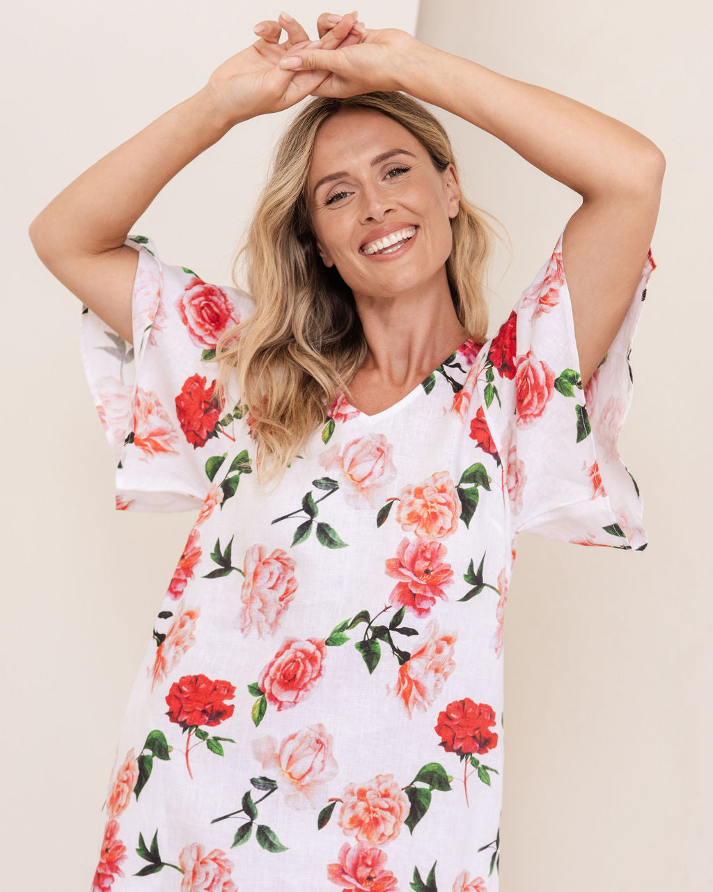 Woman wearing a See Saw linen flutter sleeve rose dress with a plain background