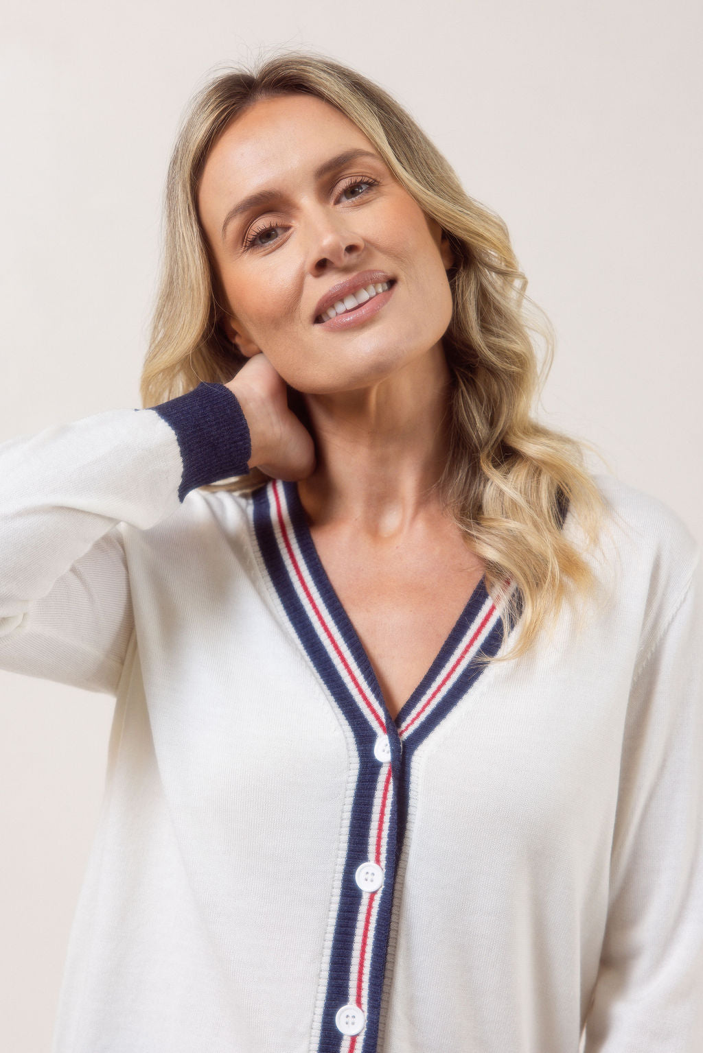 Woman wearing a white See Saw Merino Wool cardigan with blue and red accents on a plain background