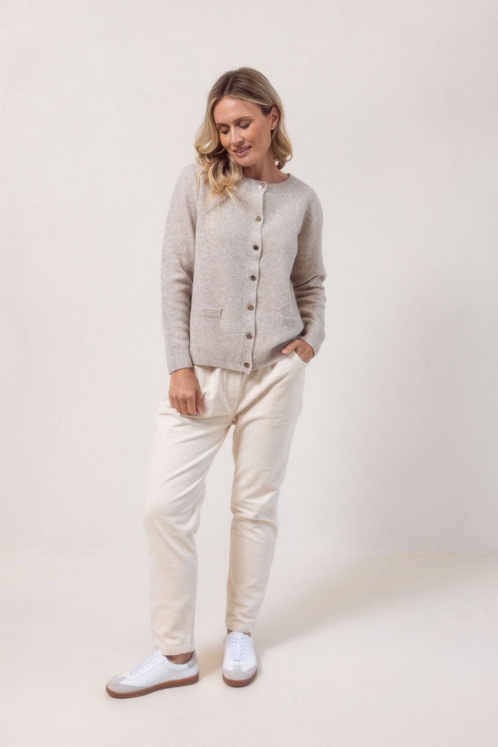 Woman wearing a wheat colour See Saw cardigan in wool and yak with buttons on a white background