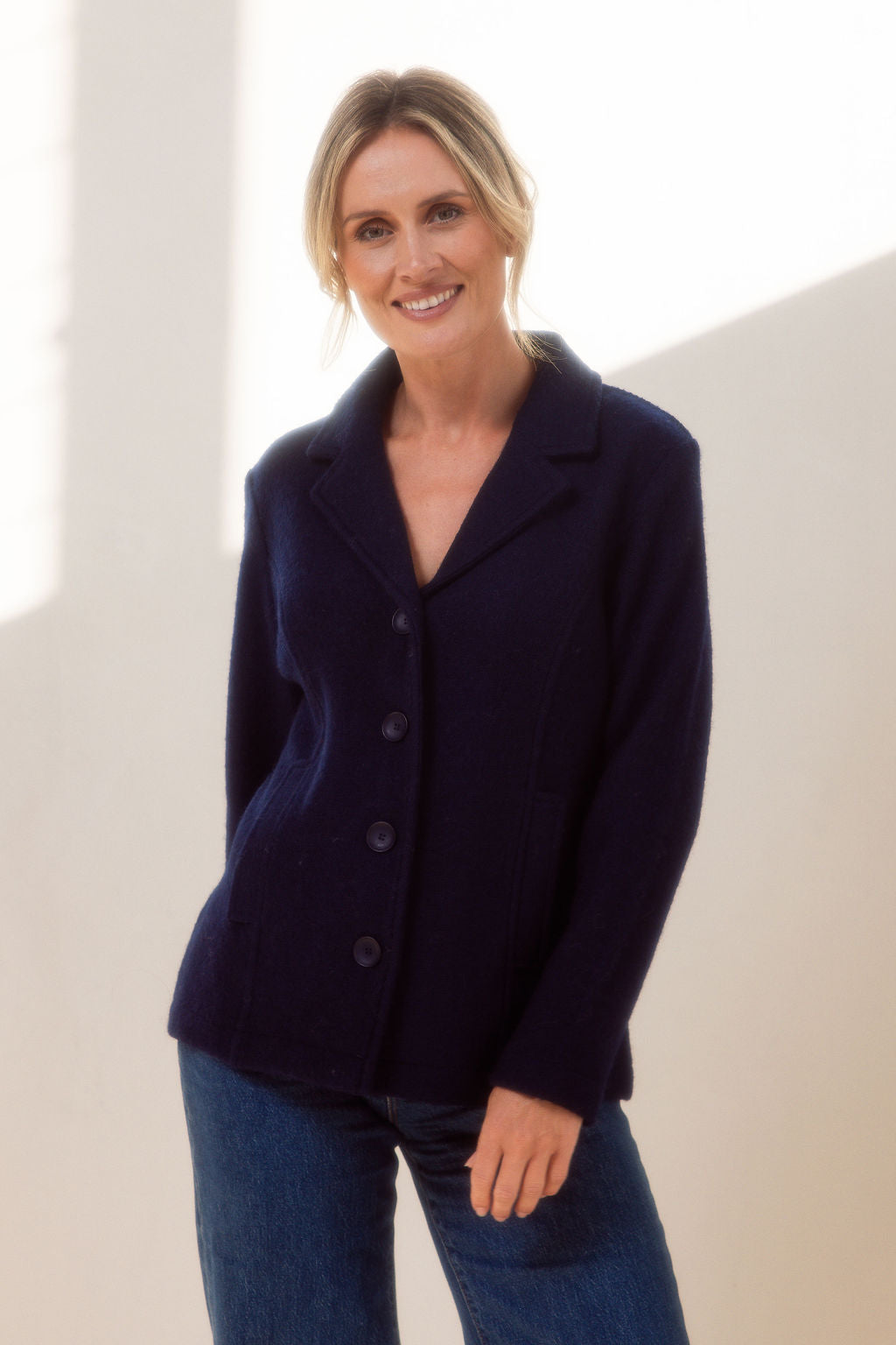 Woman wearing green boiled wool See Saw blazer in navy with a white background