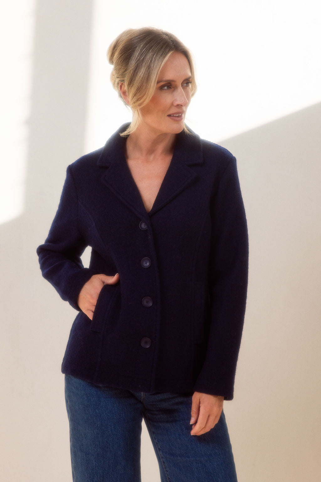 Woman wearing green boiled wool See Saw blazer in navy with a white background