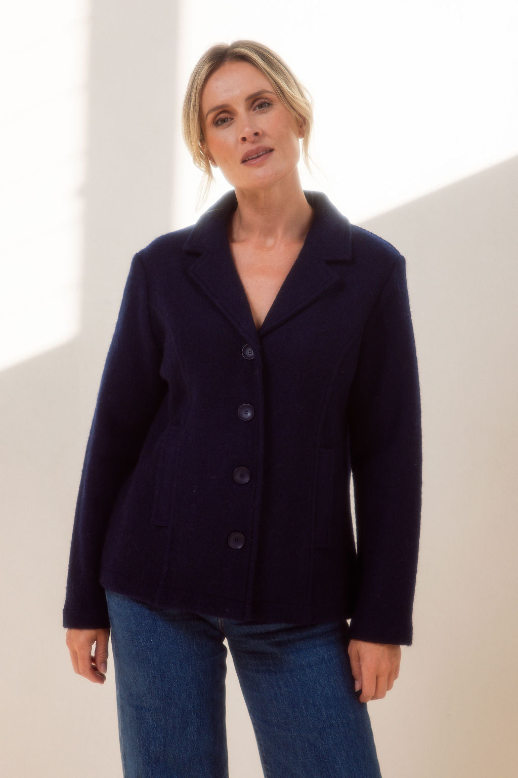 Woman wearing green boiled wool See Saw blazer in navy with a white background