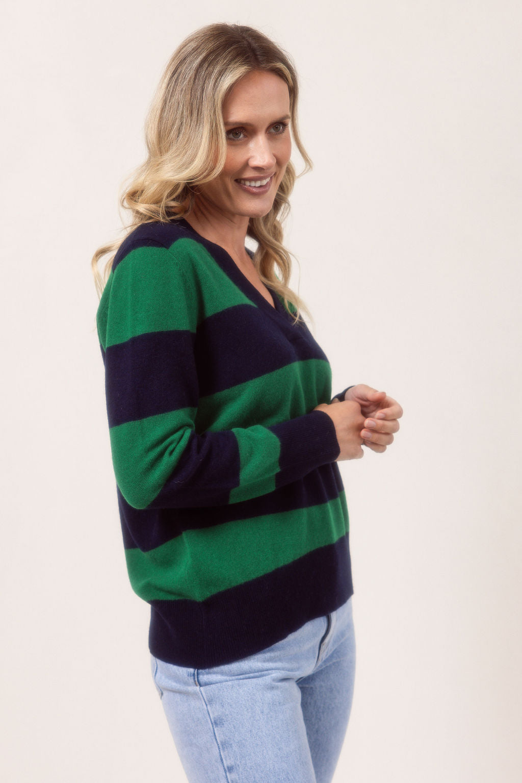 Woman wearing a striped Merino Wool See Saw sweater and jeans against a plain background