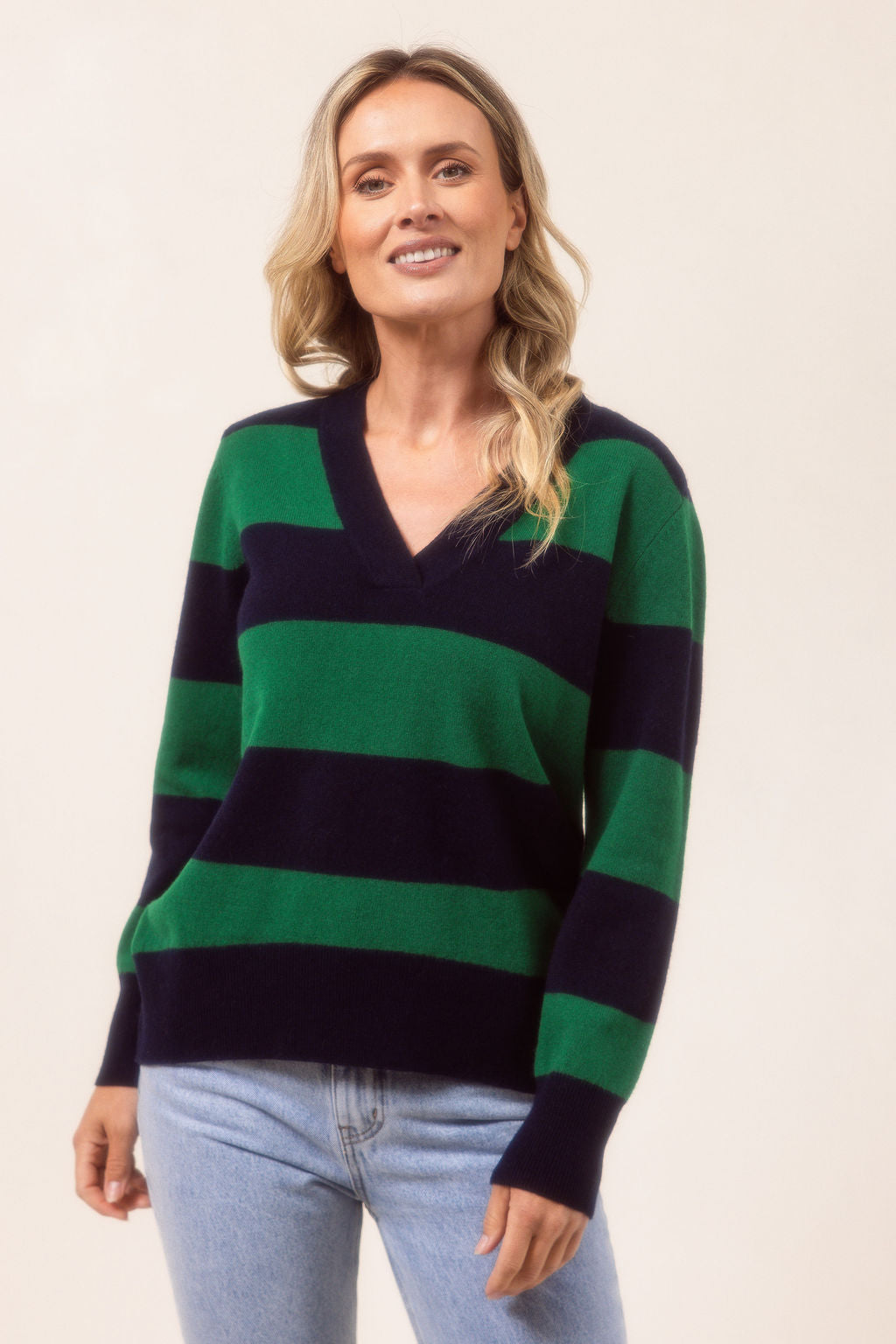 Woman wearing a striped Merino Wool See Saw sweater and jeans against a plain background