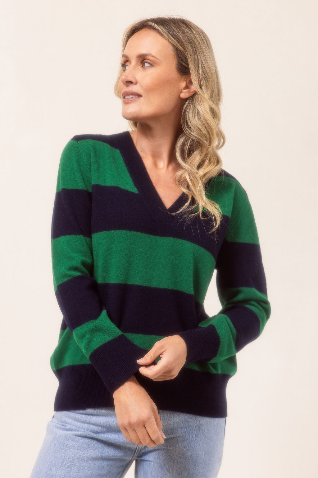 Woman wearing a striped Merino Wool See Saw sweater and beige pants against a plain background