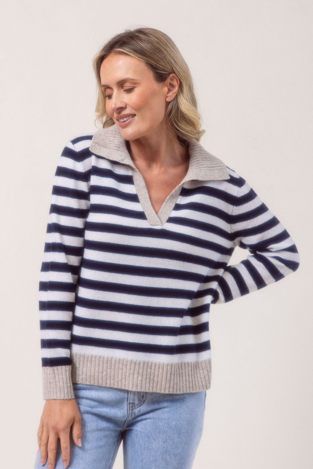 Woman wearing a see Saw Merino Wool navy and white striped sweater with a light gray collar against a plain background