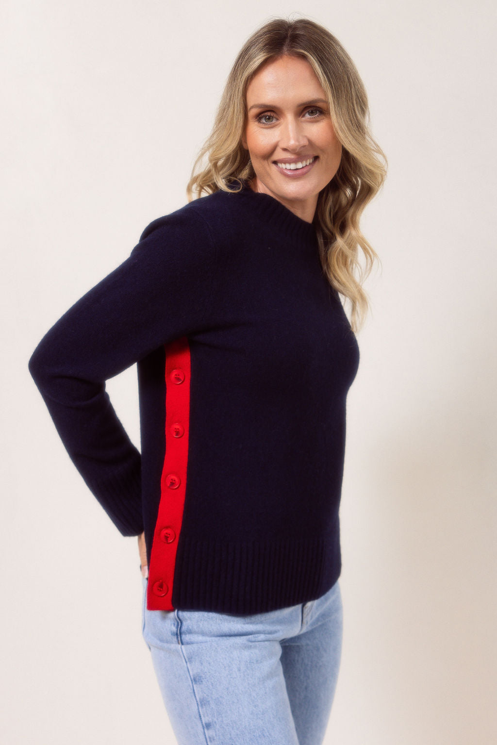 Woman wearing a Merino Wool See Saw sweater in navy sweater with red accents on a plain background
