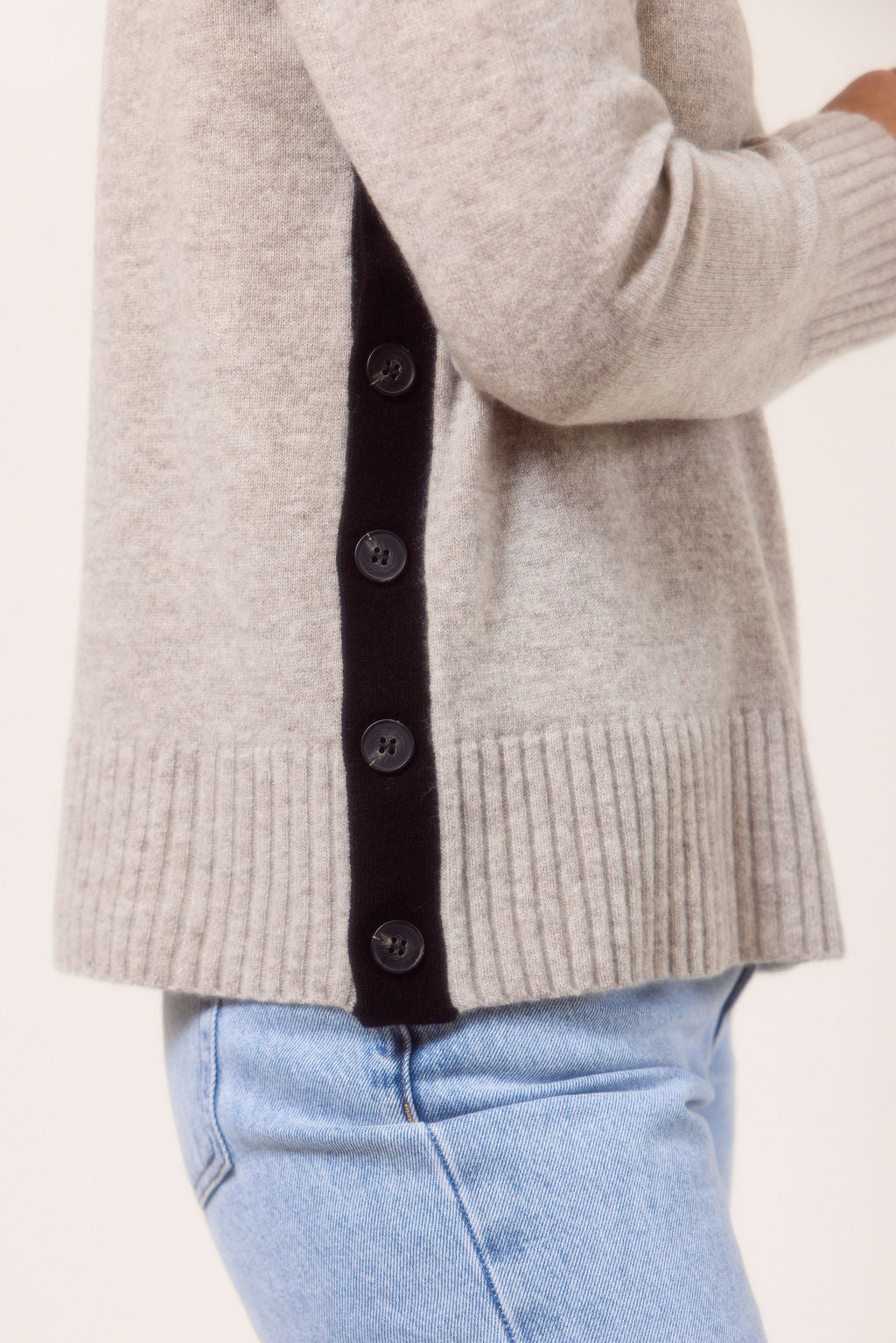 Woman wearing a Merino Wool See Saw sweater in wheat with Black accents on a plain background