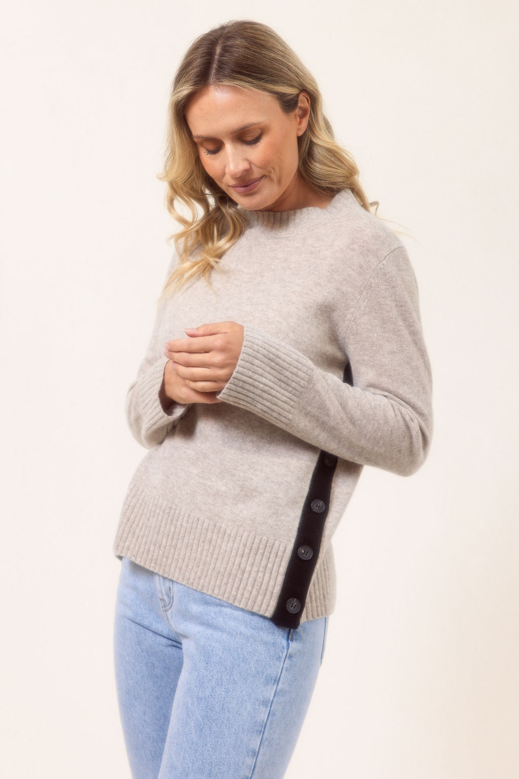 Woman wearing a Merino Wool See Saw sweater in wheat with Black accents on a plain background