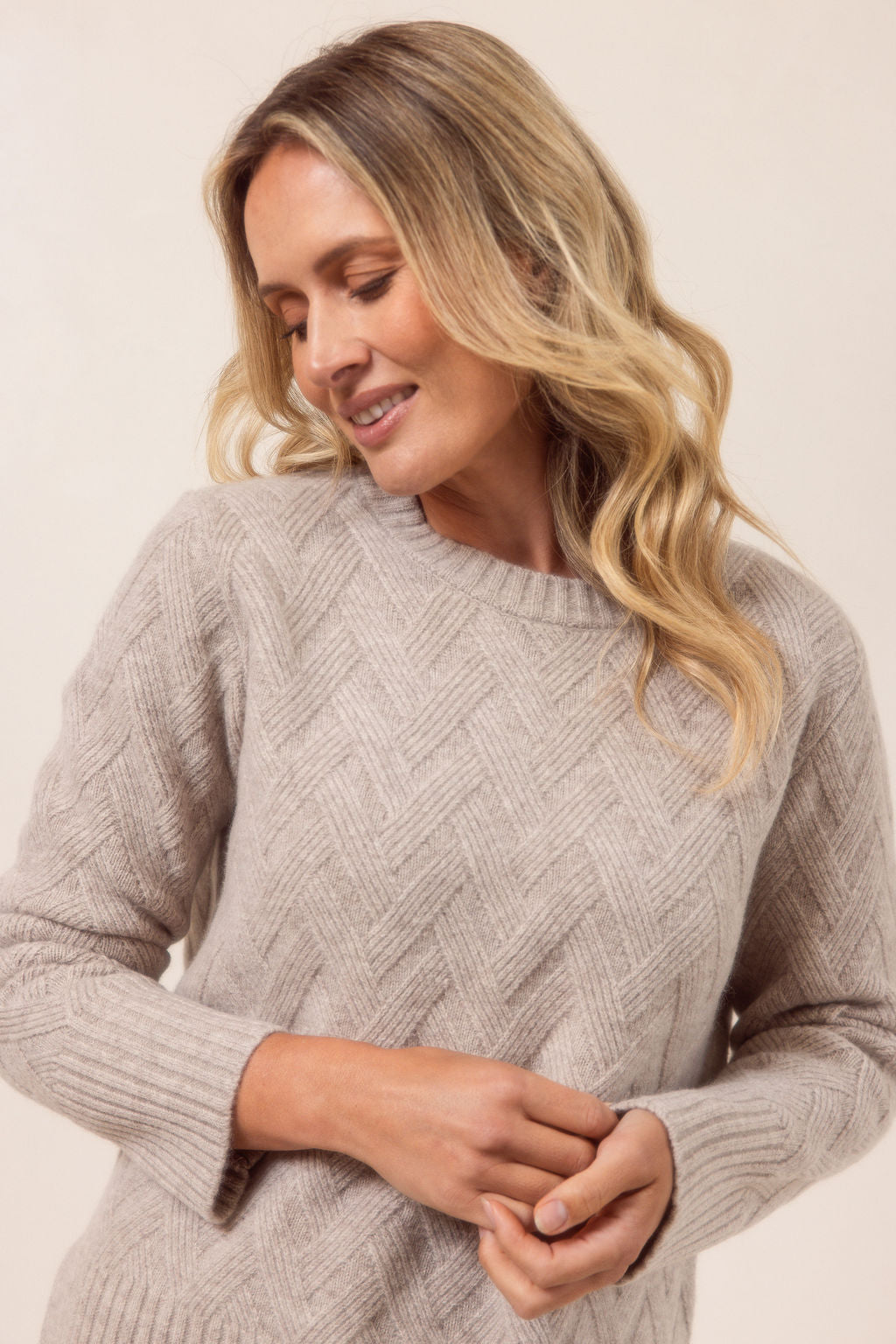 Woman wearing a beige See Saw sweater against a plain background