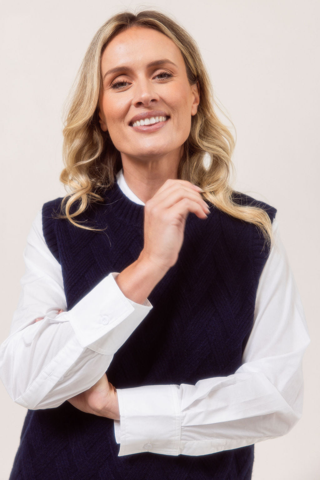 Woman wearing a See Saw Navy Merino Wool knitted vest over a white shirt on a plain background