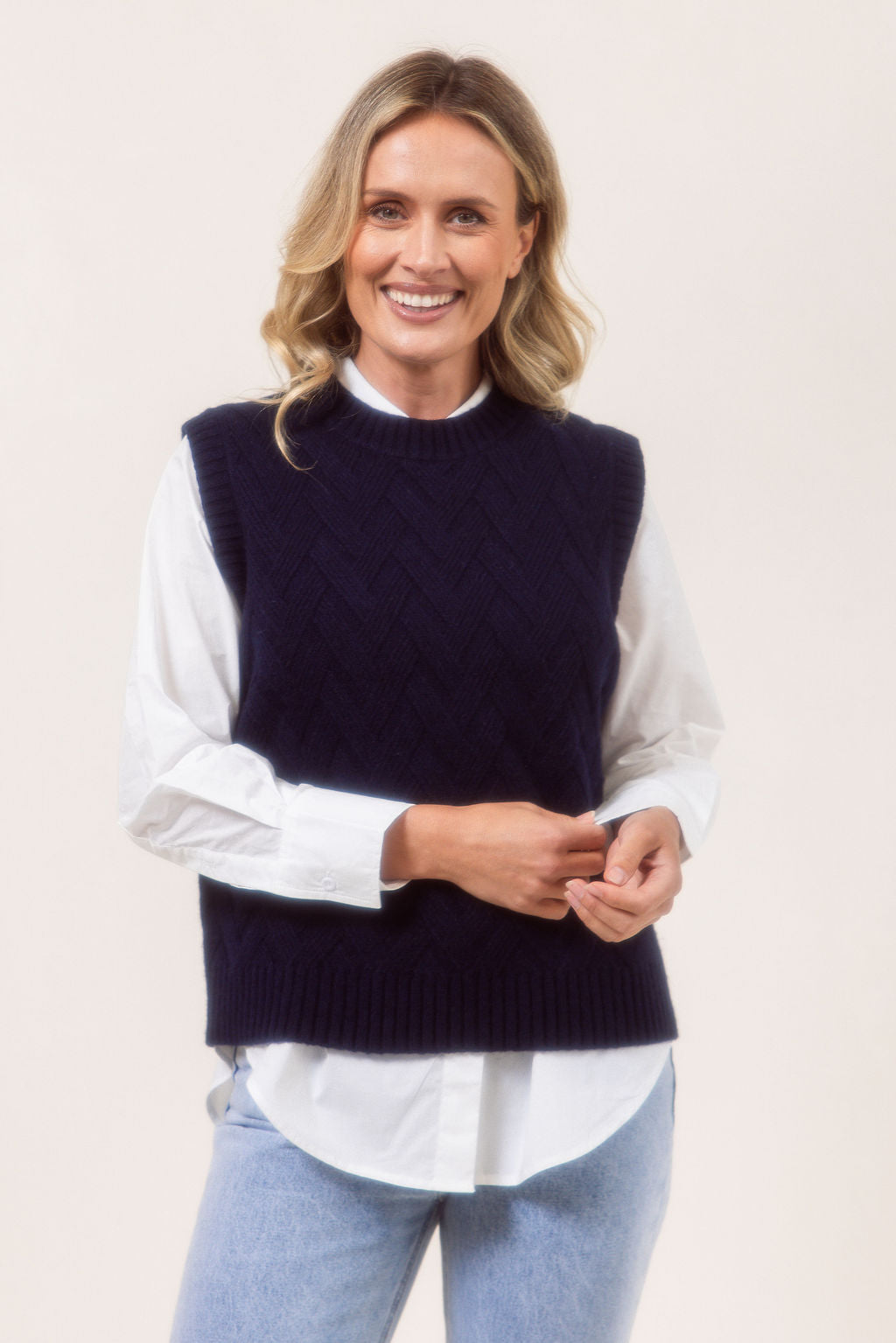 Woman wearing a See Saw Navy Merino Wool knitted vest over a white shirt on a plain background
