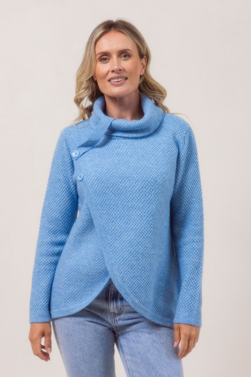 Woman wearing a powder blue Cowl Neck Moss Stitch See Saw sweater with a white background