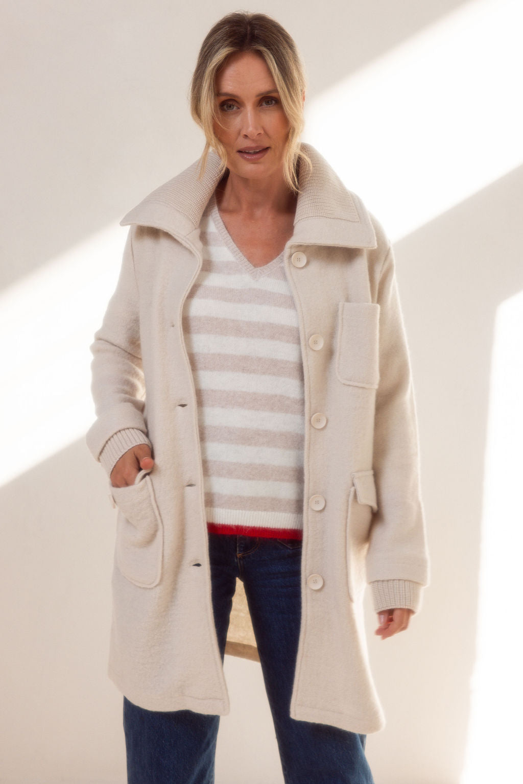 Woman wearing a beige See Saw boiled wool coat and sweater against a light background