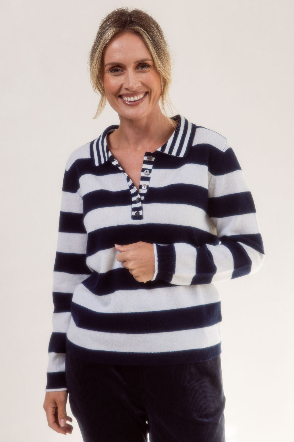 Woman wearing a merino wool See Saw black and white striped sweater on a plain background