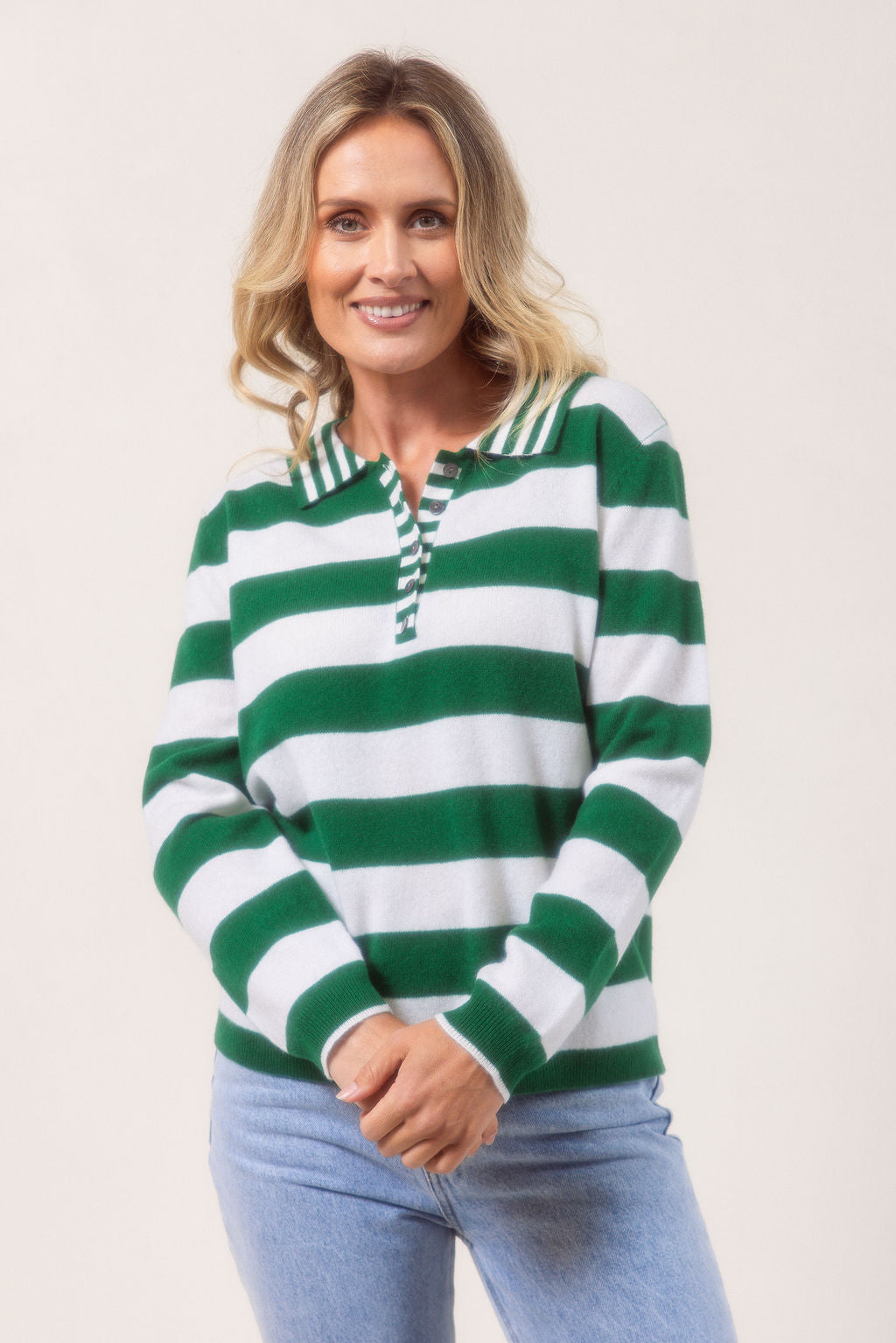Woman wearing a merino wool See Saw green and white striped sweater on a plain background