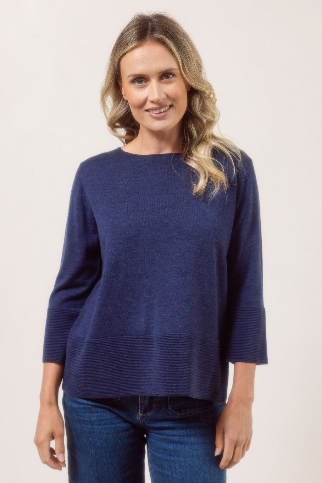 Woman wearing a indigo See Saw Merino Wool  sweater and patterned scarf against a white background