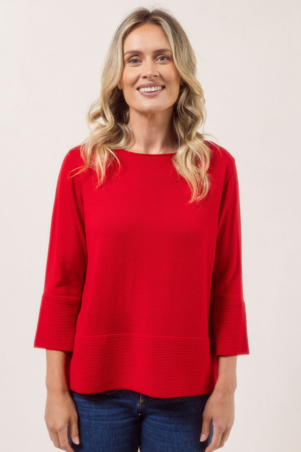 Woman wearing a red See Saw Merino Wool  sweater and patterned scarf against a white background