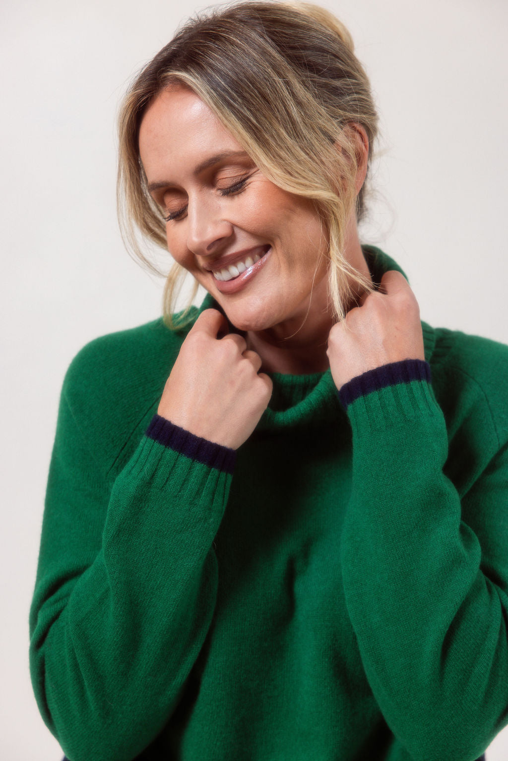 Woman wearing a Green See Saw Merino Wool sweater with a striped design on a white background