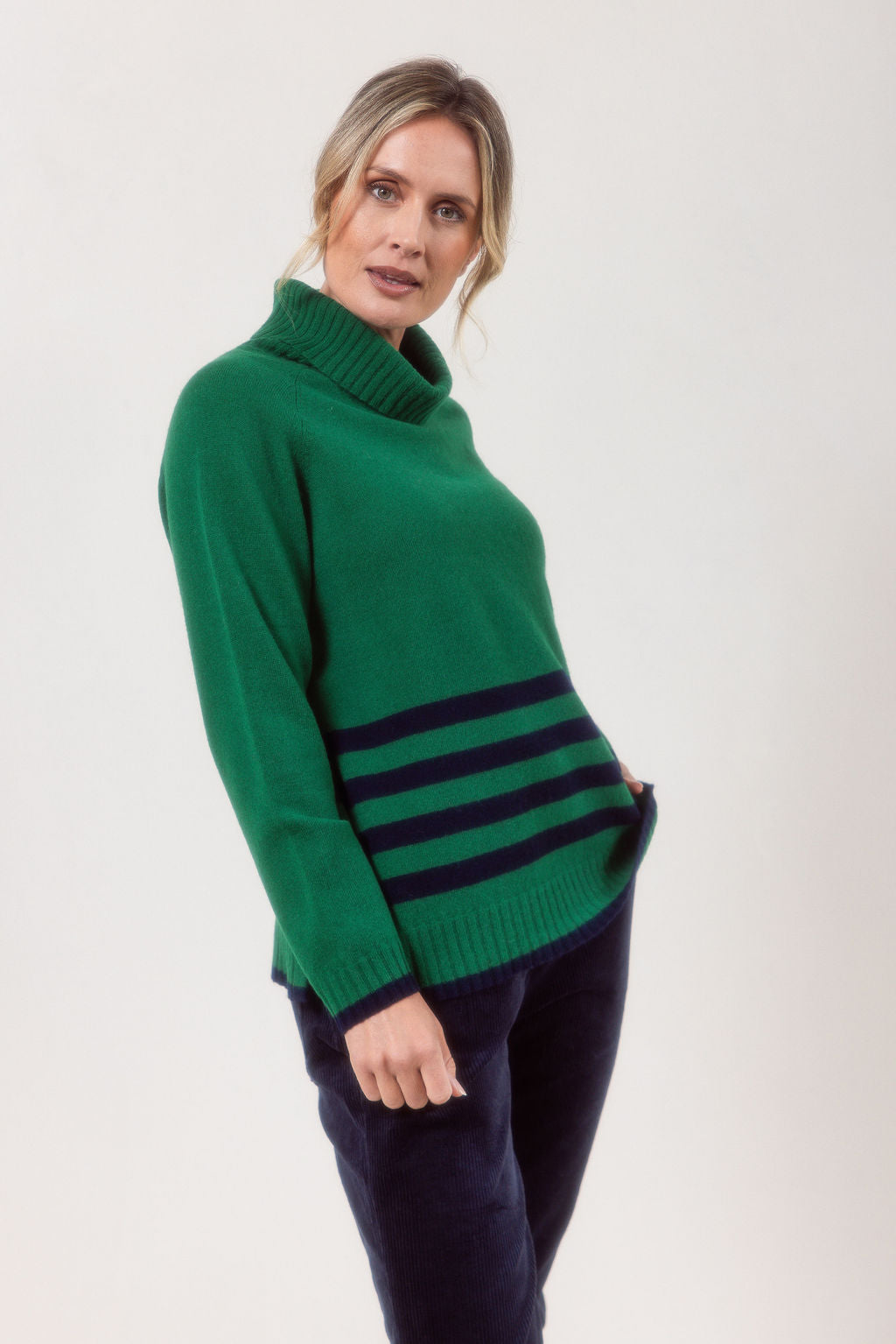 Woman wearing a Green See Saw Merino Wool sweater with a striped design on a white background