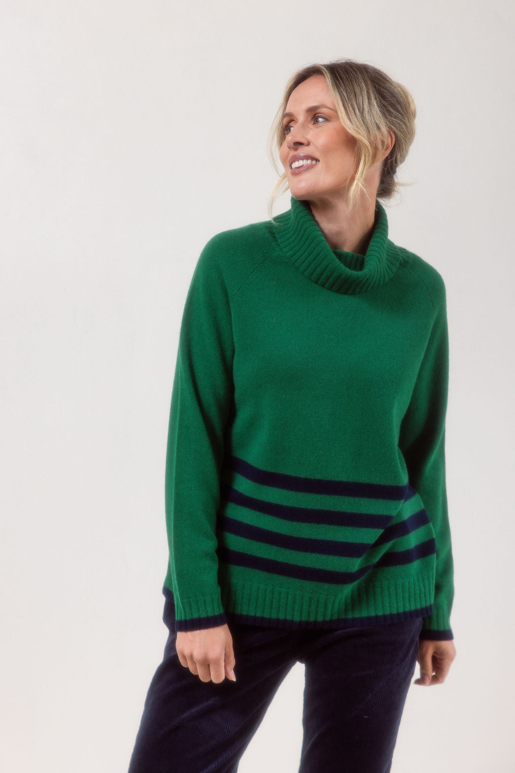 Woman wearing a Green See Saw Merino Wool sweater with a striped design on a white background
