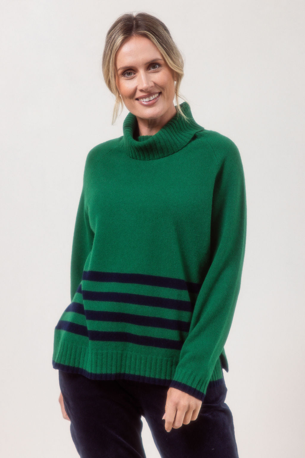 Woman wearing a Green See Saw Merino Wool sweater with a striped design on a white background
