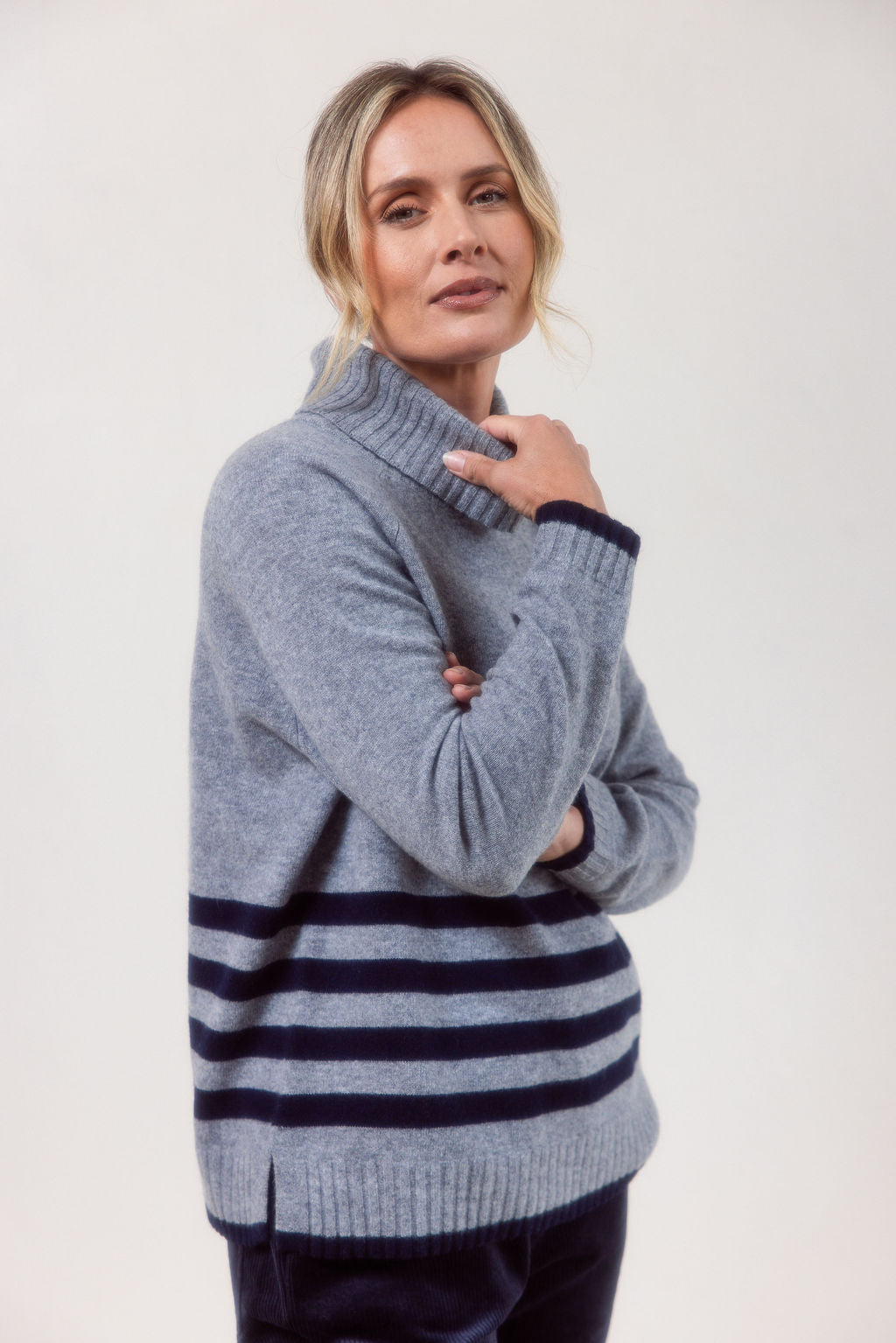 Woman wearing a silver See Saw Merino Wool sweater with a striped design on a white background