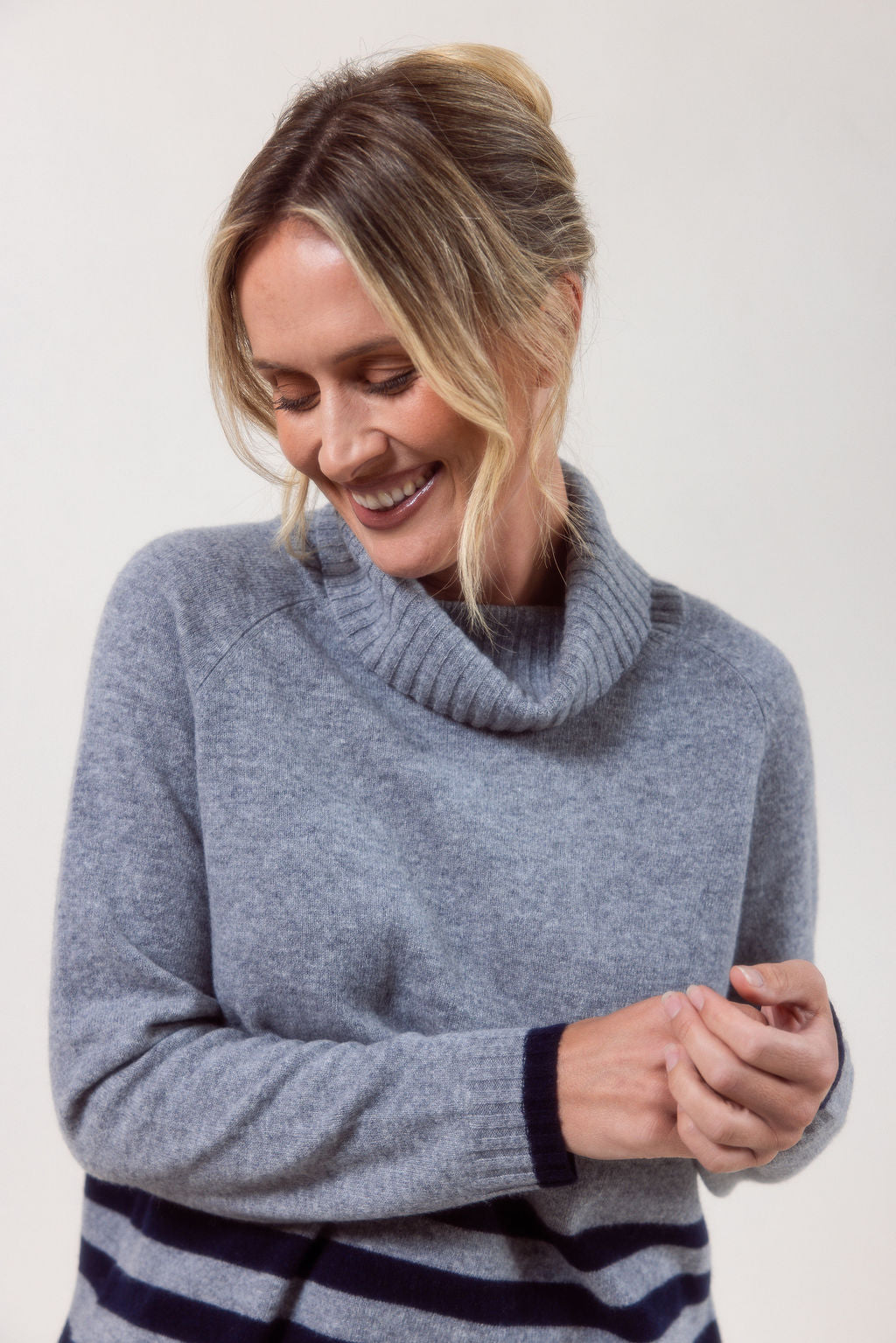 Woman wearing a silver See Saw Merino Wool sweater with a striped design on a white background