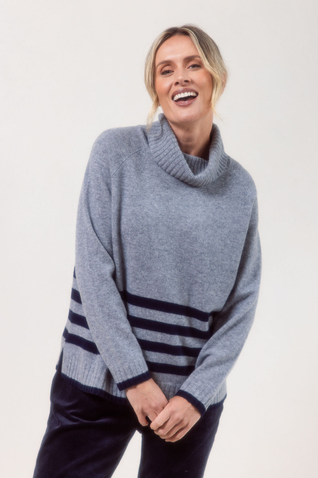 Woman wearing a silver See Saw Merino Wool sweater with a striped design on a white background