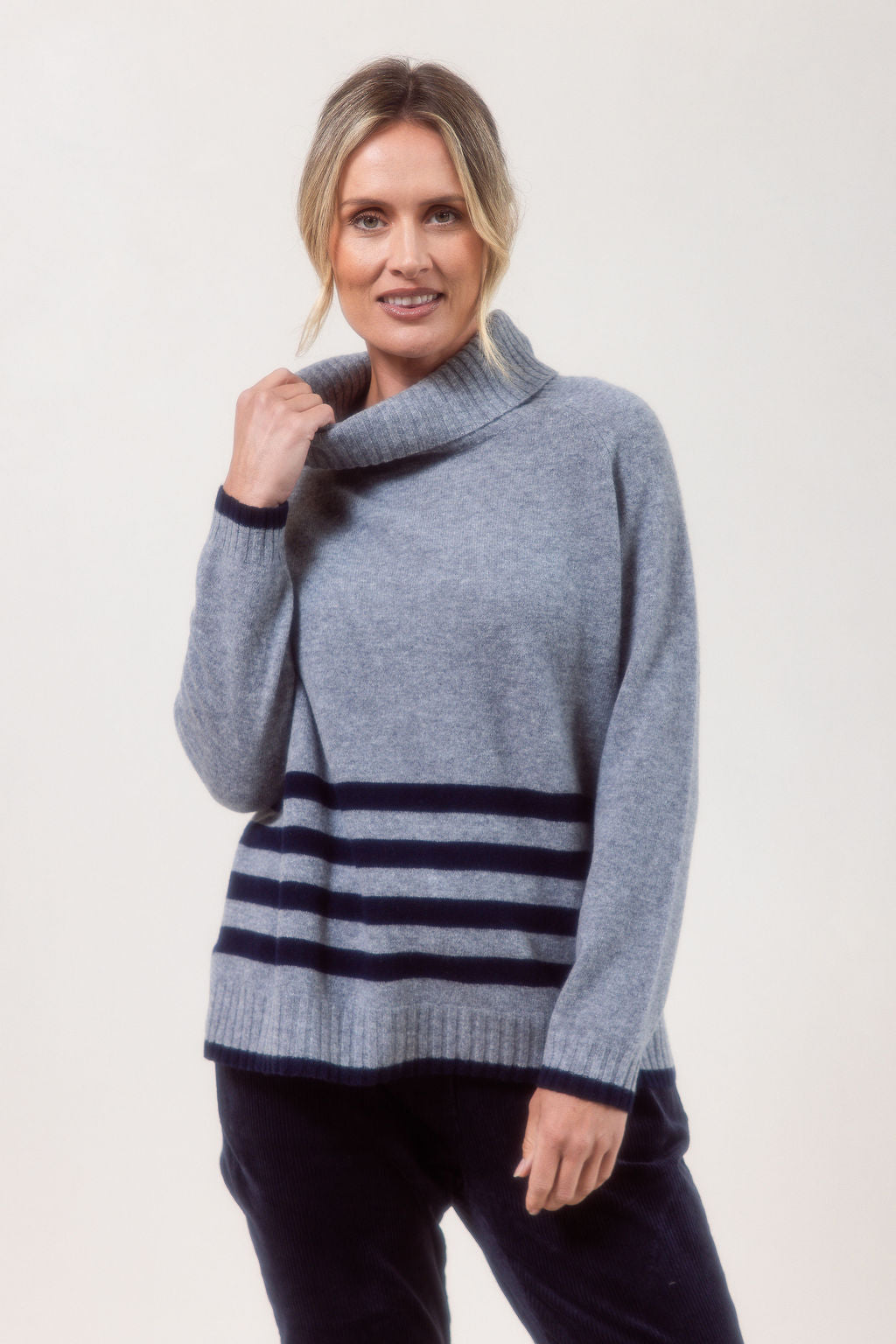 Woman wearing a silver See Saw Merino Wool sweater with a striped design on a white background