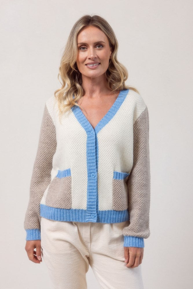 Woman wearing a Moss Stitch See Saw powder blue and beige cardigan with brown accents on a white background