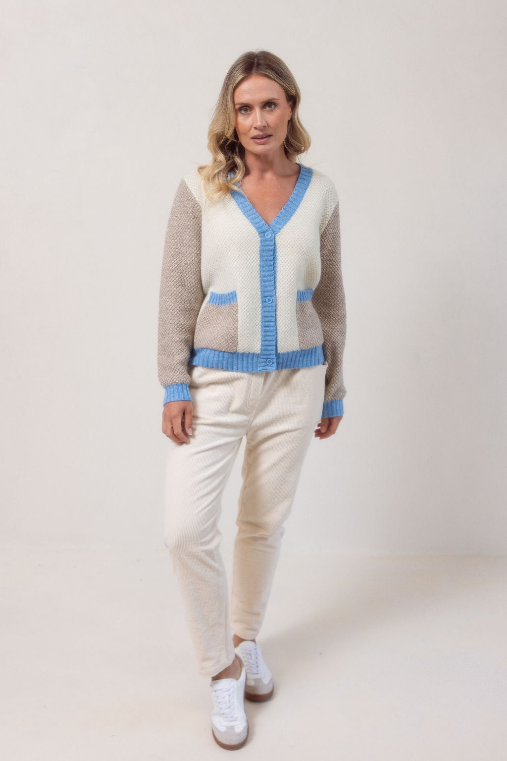 Woman wearing a Moss Stitch See Saw powder blue and beige cardigan with brown accents on a white background