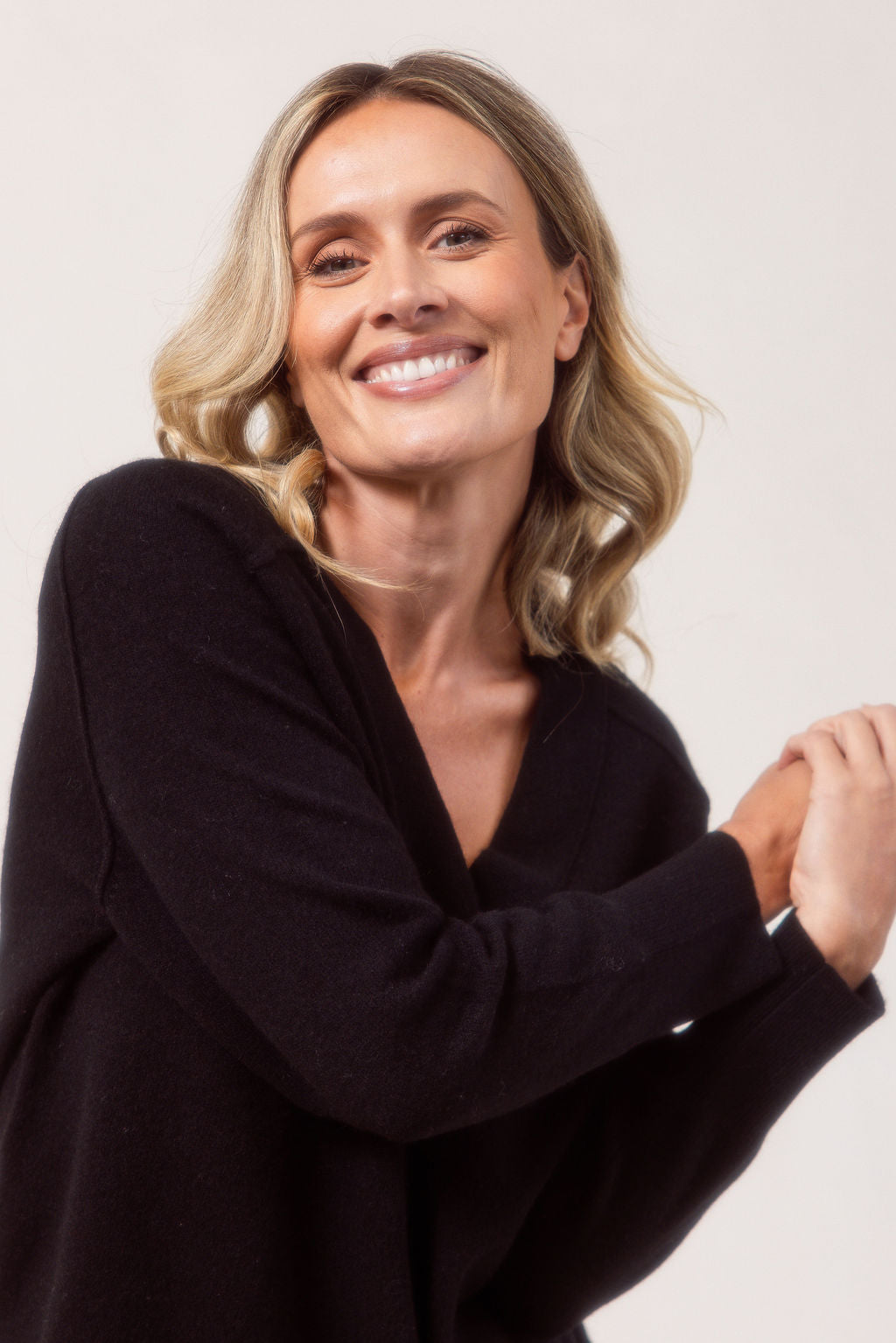 Woman wearing a v neck Merino wool See Saw Navy sweater against a plain background