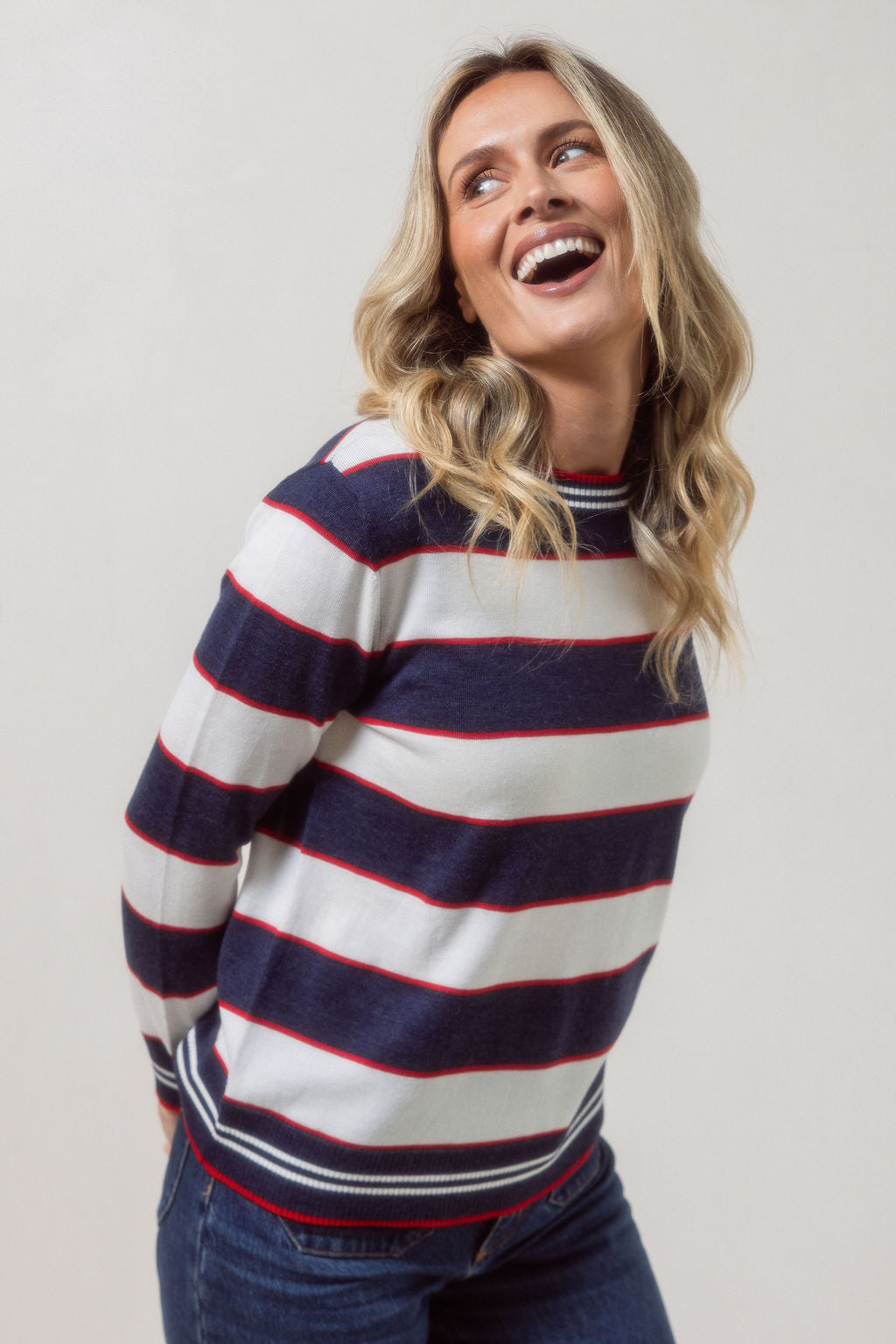 Woman wearing a striped merino wool See Saw sweater with a plain background