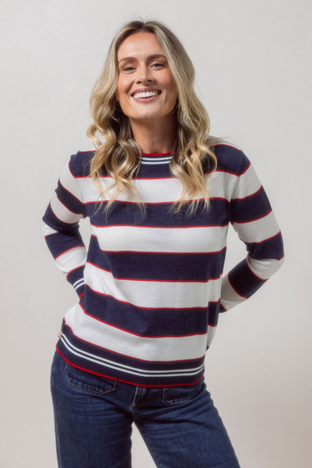 Woman wearing a striped merino wool See Saw sweater with a plain background
