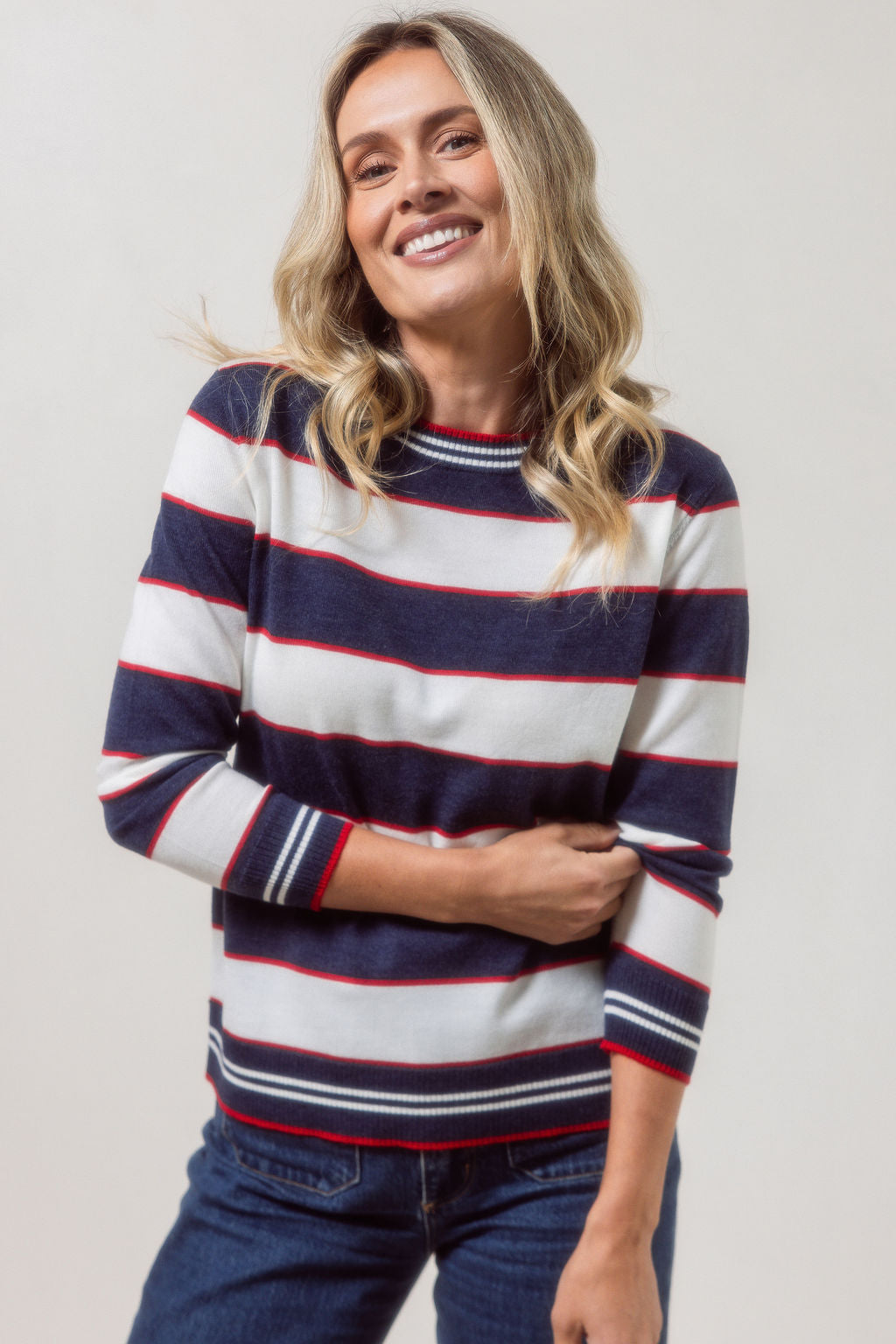 Woman wearing a striped merino wool See Saw sweater with a plain background
