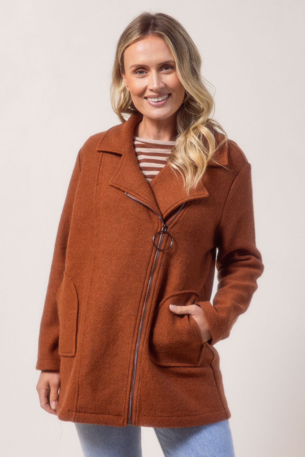 Woman wearing a copper See Saw boiled wool coat against a plain background