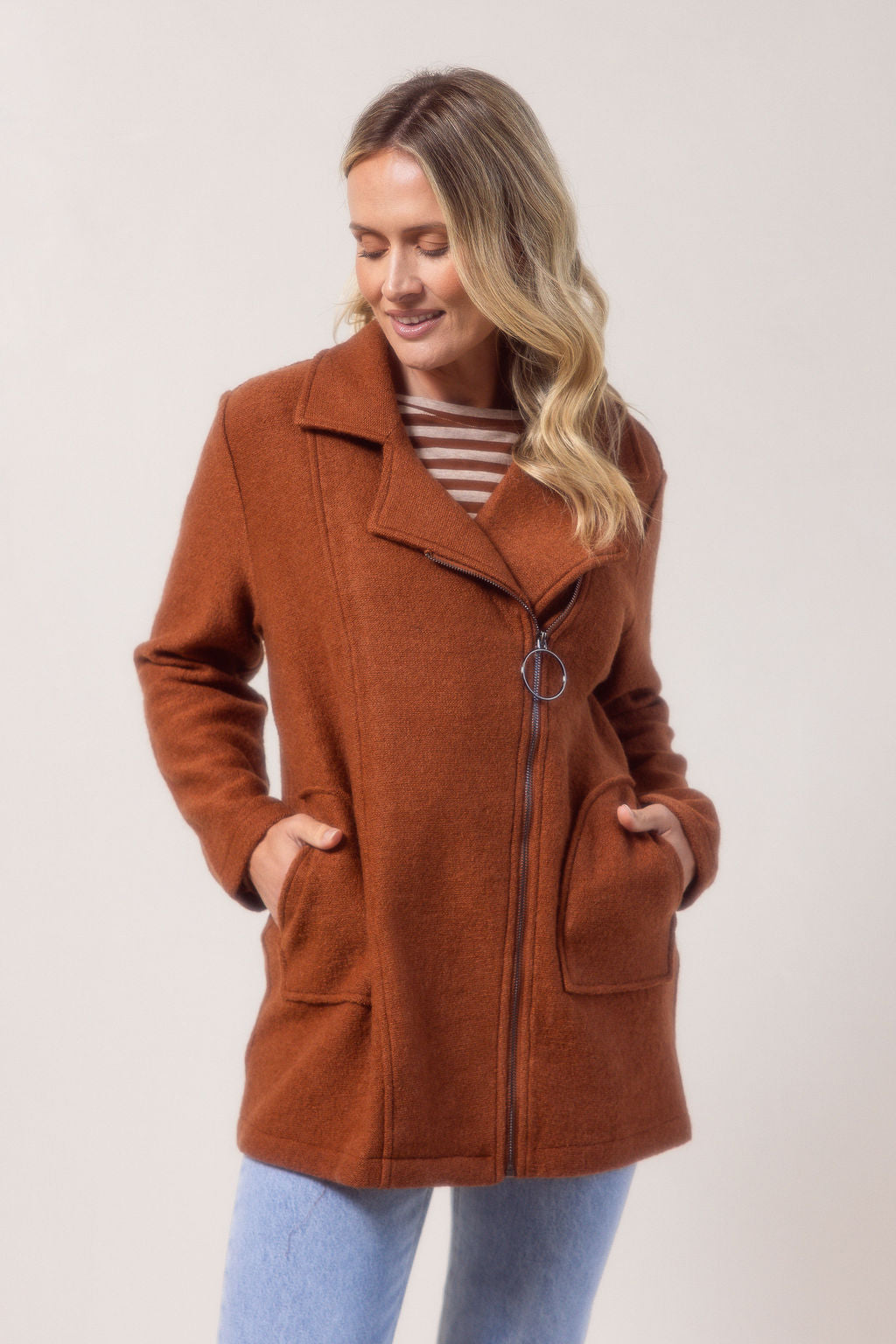 Woman wearing a copper See Saw boiled wool coat against a plain background