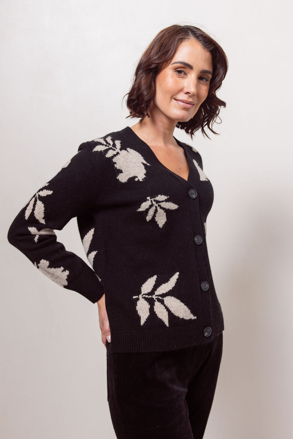 Woman wearing a black See Saw cardigan with white floral patterns against a plain background