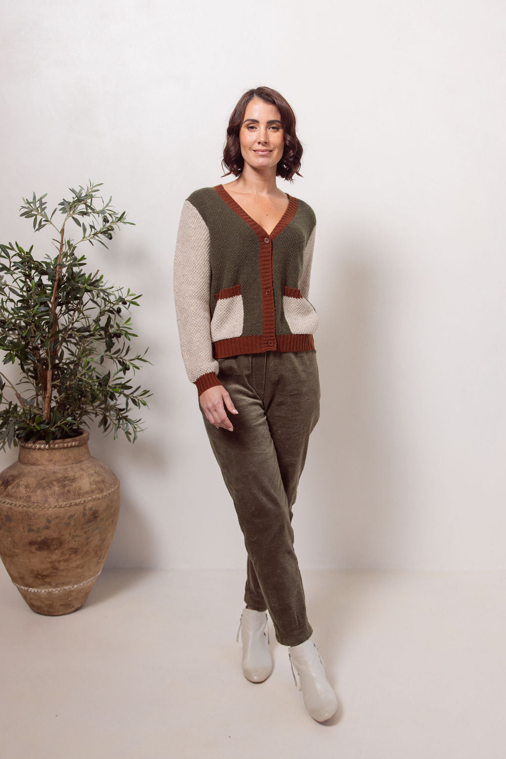 Woman wearing a Moss Stitch See Saw green and beige cardigan with brown accents on a white background