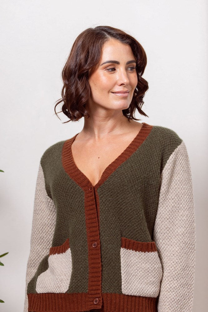 Woman wearing a Moss Stitch See Saw green and beige cardigan with brown accents on a white background