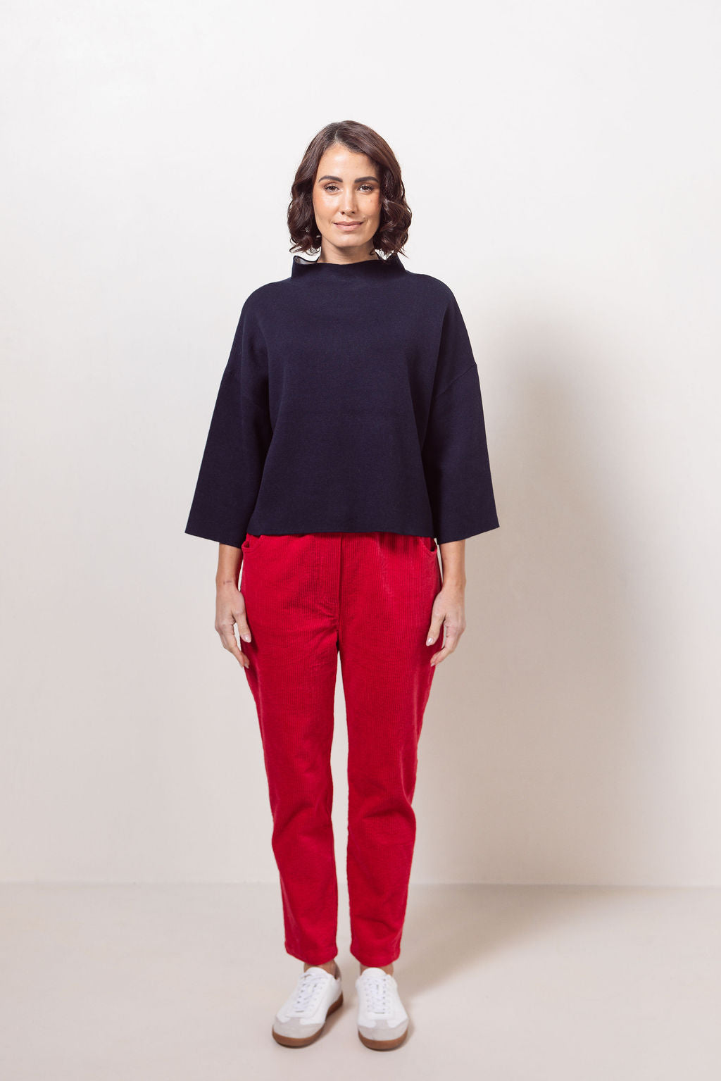 Woman wearing a See Saw knit and red corduroy jogger pants against a white background